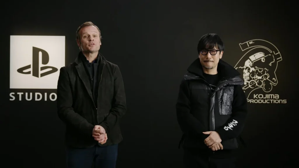 Hermen Hulst e Hideo Kojima lado a lado em frente aos logótipos da PlayStation Studios e da Kojima Productions.